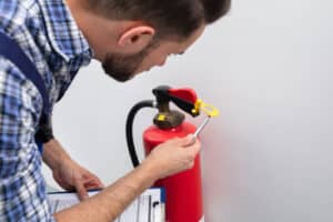 Young Male Technician Checking Symbol On Fire Extinguisher
