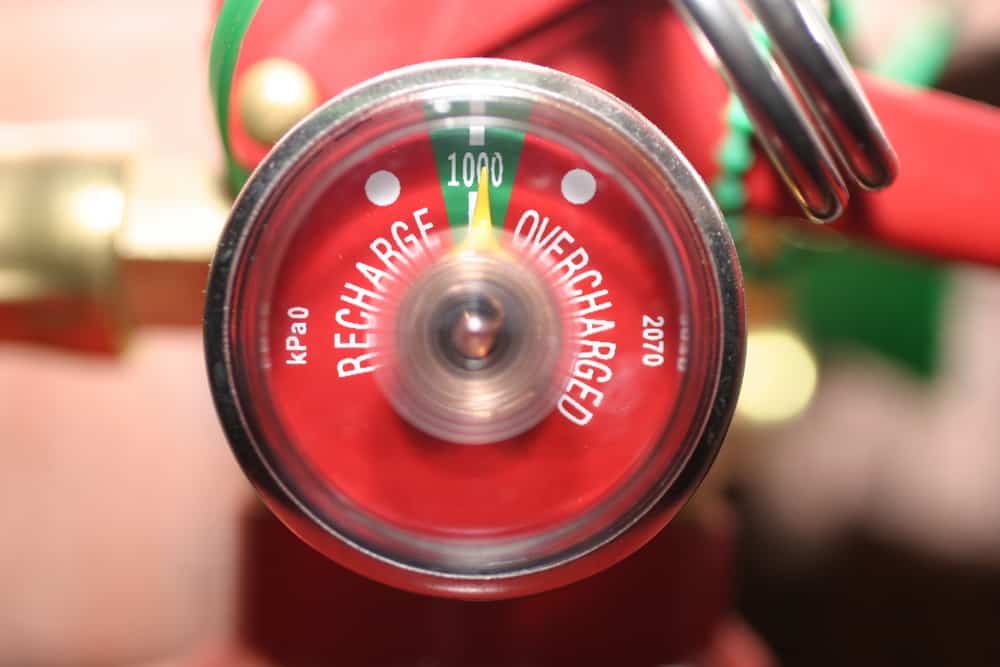 Close-up of a fire extinguisher pressure gauge, needle at the green "100%" zone for proper charge. Trust our Fire Extinguishers Sales & Service in Long Island to keep your equipment safe and fully operational.